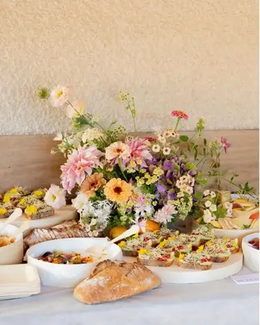 Buffet traiteur Cagettes avec bouquet de fleurs de saison, pain et assortiment salé pour un événement à Paris